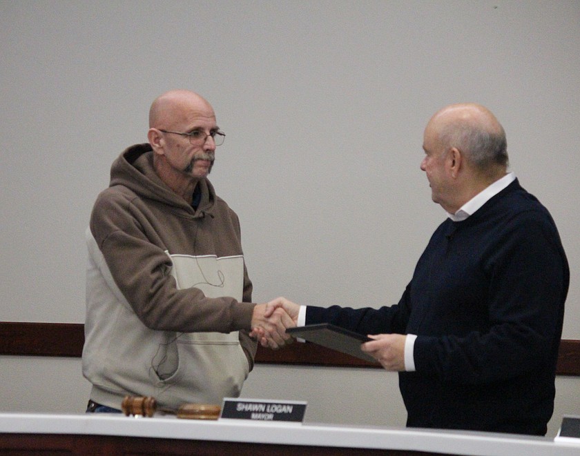 Othello City Council member Corey Everett, left, shakes hands with Othello Mayor Shawn Logan, right, after Logan thanked him for his 12 years on the council.