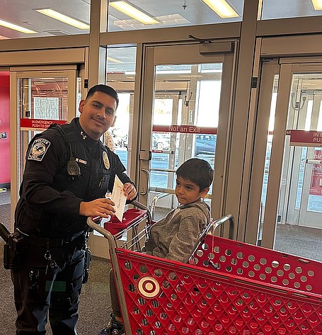 QPD officer Mark Gomez and his shopping partner prepare to set out on a quest for toys. The Quincy Police Department was able to help ten families for Christmas with its Shop with a Cop program.