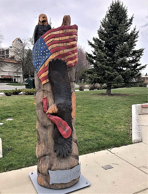 A patriotic statue, carved by artist Jeff May from the original Freedom Tree, graces the Veterans Memorial Plaza at McEuen Park. The new Freedom Tree grows in the background.