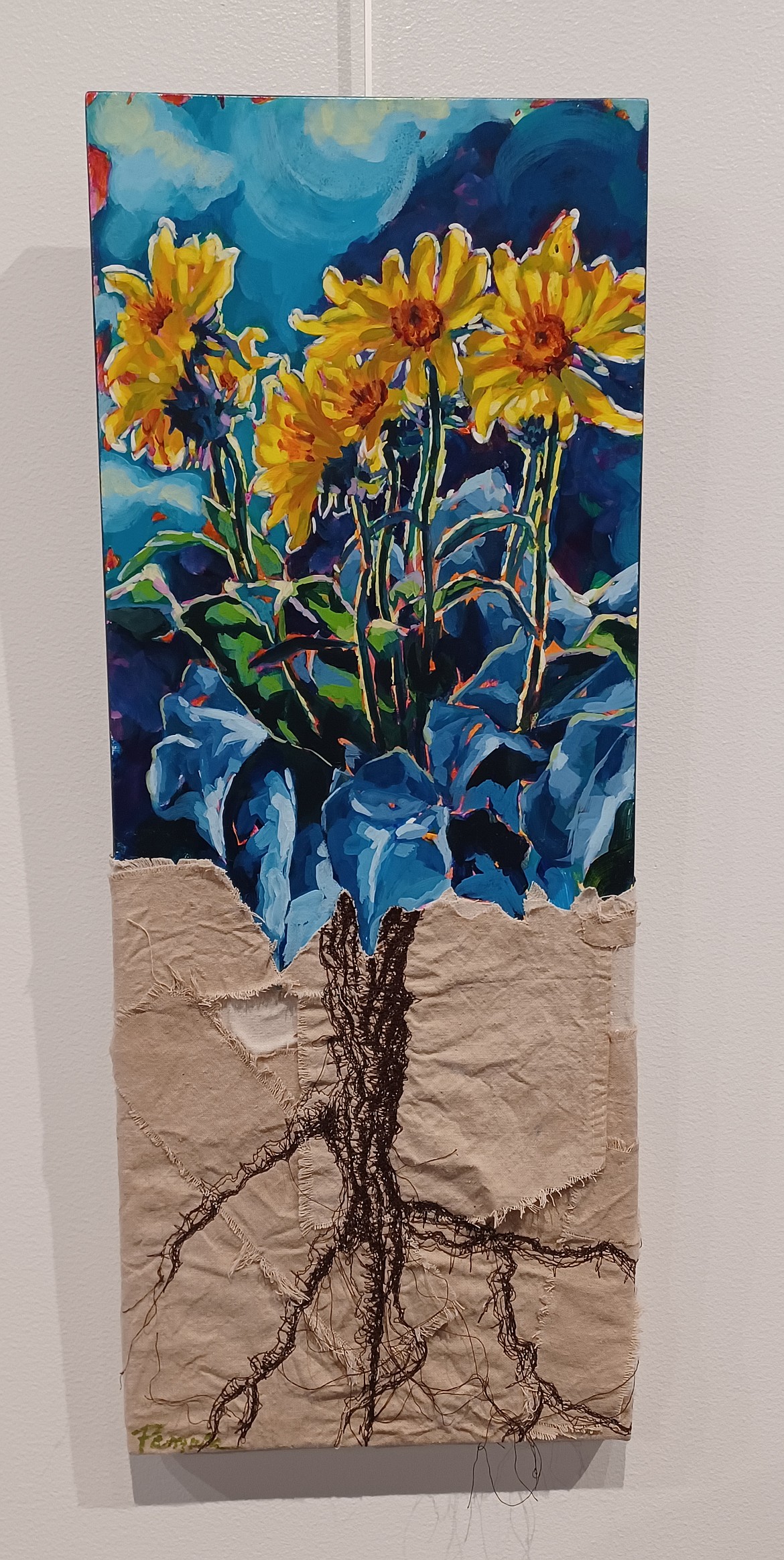 In a departure from her usual acrylic medium, Pamela Petry-McKinsey’s multimedia piece “Rooted in Knowledge” shows the deep unseen roots that underlie a bright bunch of flowers.