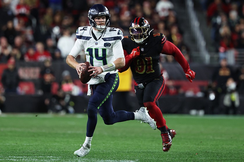 Seattle Seahawks quarterback Sam Darnold (14) rolls out to pass while pressured by San Francisco 49ers defensive tackle Sam Okuayinonu (91) during the second half of an NFL football game in Santa Clara, Calif., Saturday, Jan. 3, 2026.