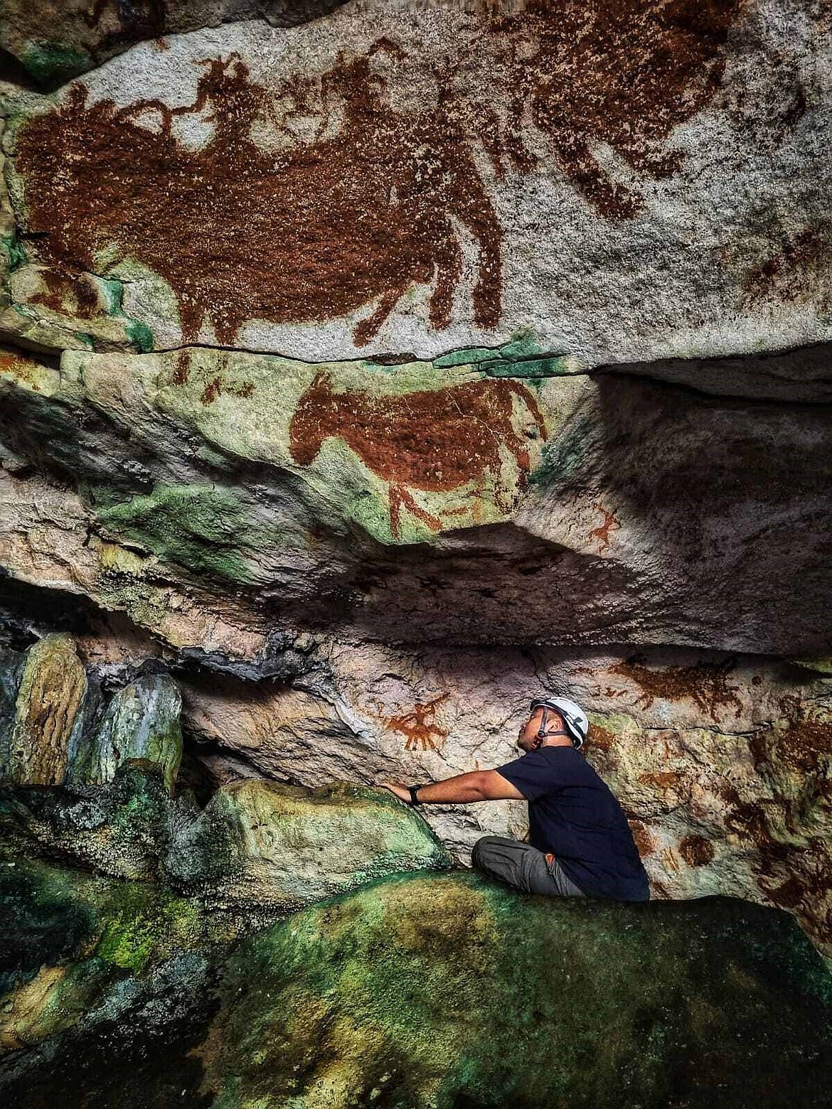 This image provided by Maxime Aubert shows scientist Shinatria Adhityatama studying cave art found in Sulawesi, Indonesia.