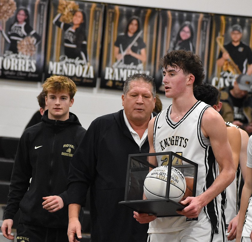 Royal junior Grant Wardenaar (24) walks toward the center of the court holding a basketball celebrating his achievement in breaking the all-time scoring record at Royal High School. Wardenaar was joined by Head Coach Tim Ravet, left of Wardenaar, and the entire Knights team on the court as they honored his milestone.