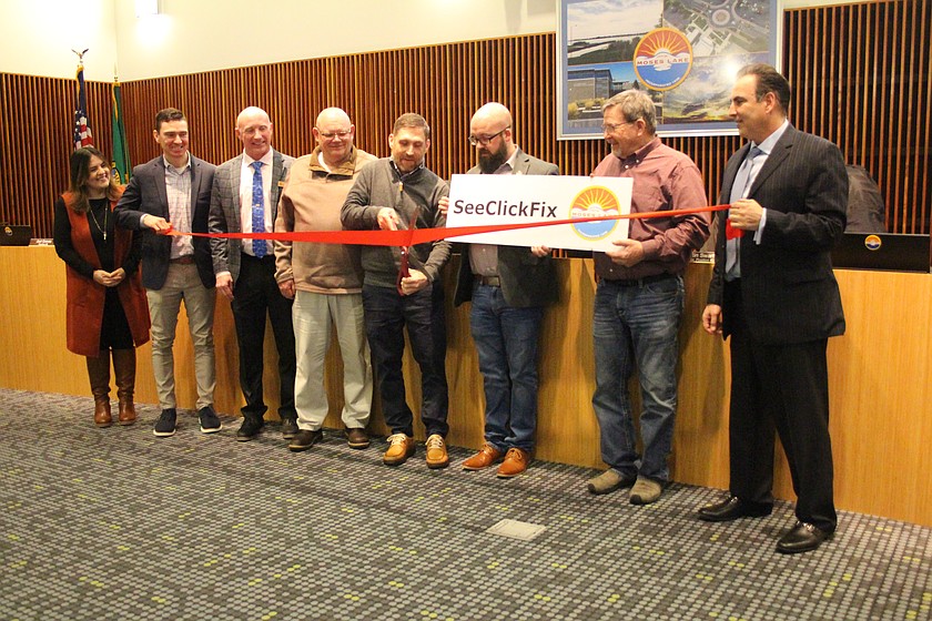 Moses Lake Mayor Dustin Swartz, center, cuts the ribbon for the new See, Click, Fix program, surrounded by, from left, Lizbeth Murillo-Busby and council members Joel Graves, Jeremy Davis, Mark Fancher, Don Myers, David Skaug and Victor Lombardi.