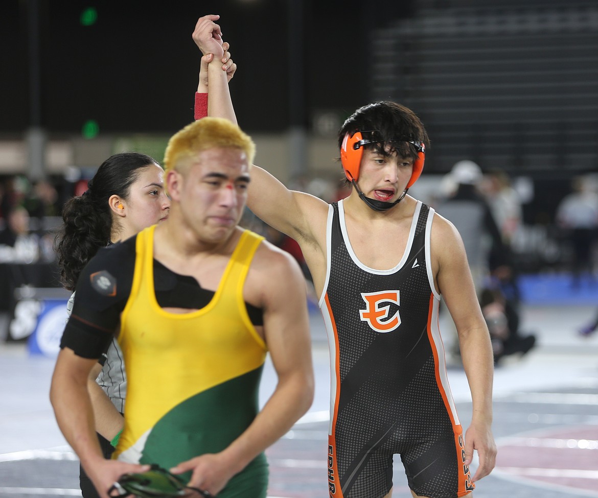 Carter Garcia, in black and orange, has his hand raised after earning a win at the Mat Classic tournament.