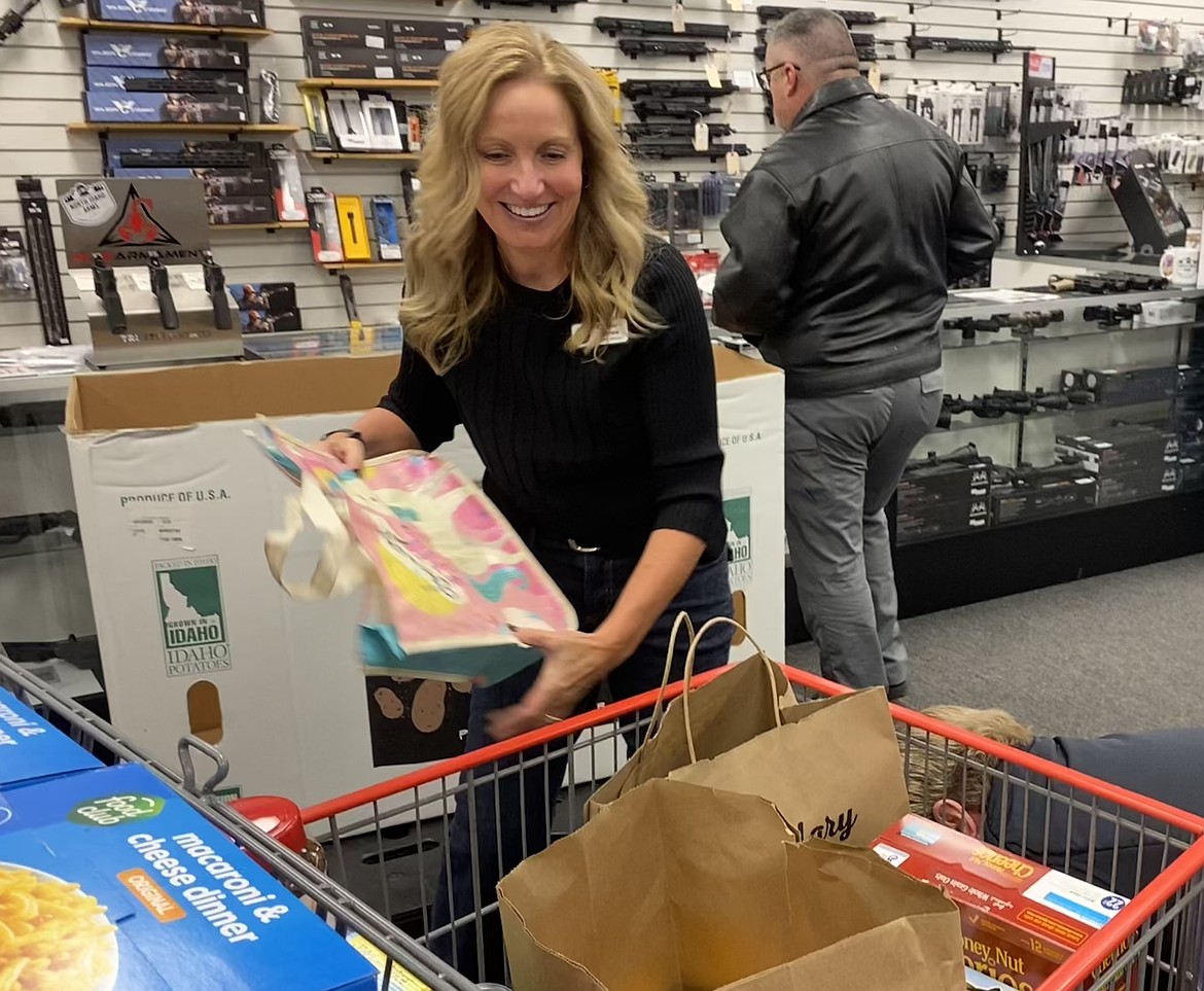 3rd Avenue Marketplace Executive Director Charlene Holbrook places donated groceries into a cart at North Idaho Arms during a food drive. Holbrook is retiring from the position as of March 1.