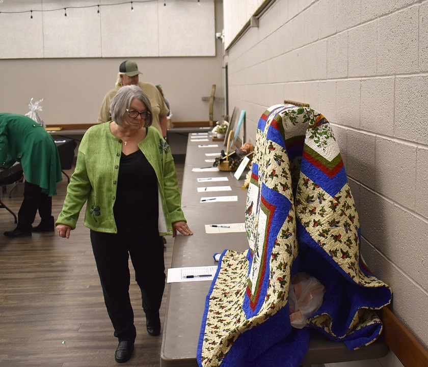 Becky Harris looks over silent auction items at the Quincy Food Bank’s Golden Giving auction Saturday. Seventy-five items were donated by community members for the auction.