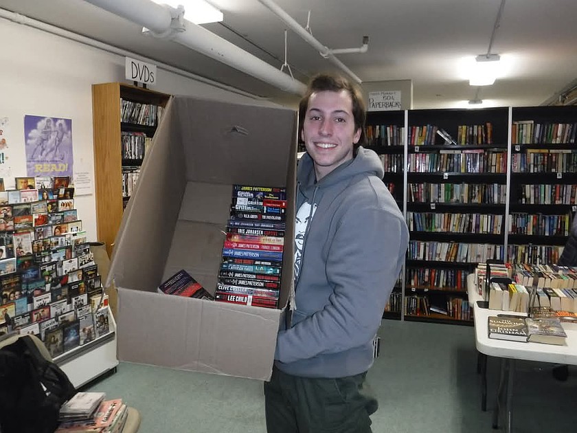Bryson Fico of Okanogan holds up some of the books he’s collected for jails through his Pages of Redemption initiative.