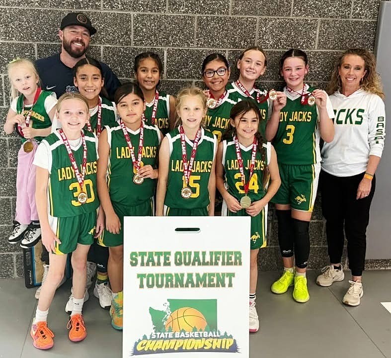 The Quincy Jacks fifth-grade girls basketball team and their coaches stand together, celebrating their second-place finish at a previous tournament to qualify for the state basketball championships.