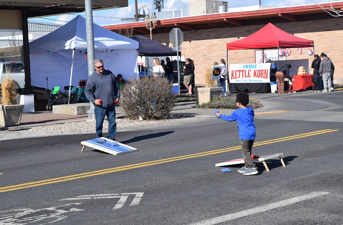 A couple of attendees get in a game of bean bag toss at Brews & Tunes Saturday.