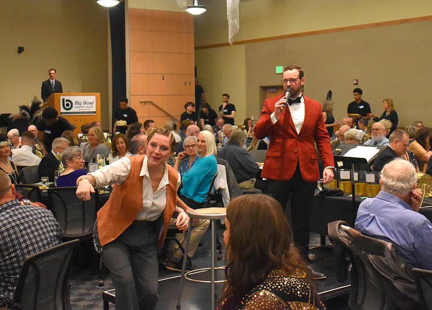 Spotter Chelsea Yarbro, left, calls out a bid to auctioneer Jacob Barth, right, at the Big Bend Community College Foundation’s Cellarbration! for Education auction Saturday.