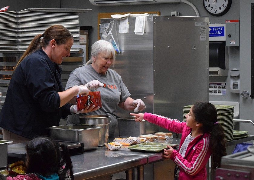 A student goes through the Grant Elementary food service line Tuesday with help from Cynthia Berrett, left, and Shelley Fairchild, right. She chooses from a walking taco, enchilada, or a sandwich. Every day students have three lunch options.