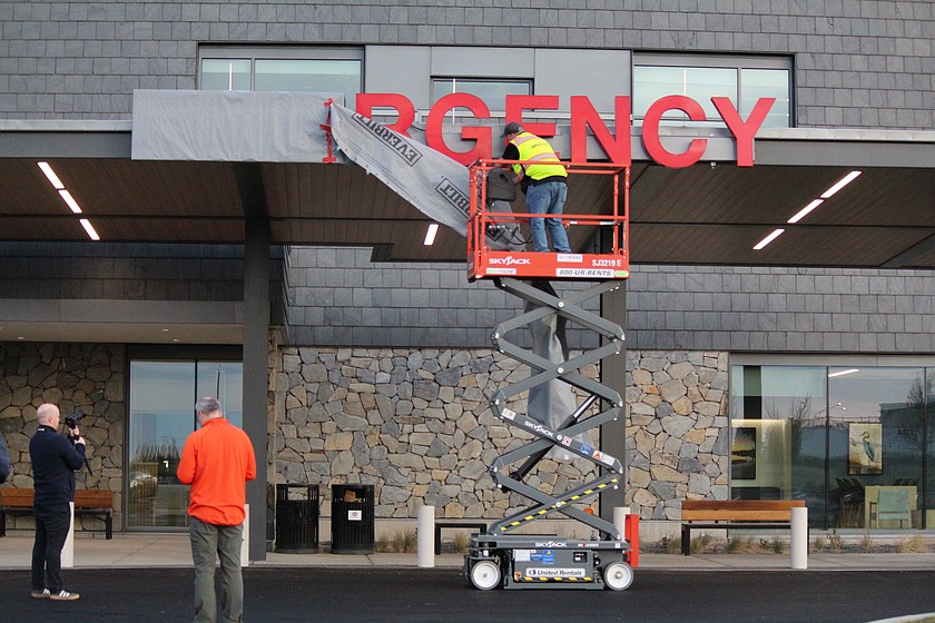 Jason Wilbur, Graham Construction, removes the cover from the Emergency department sign at the new Samaritan Hospital March 6. Moving expenses contributed to an operating loss for Samaritan in February.