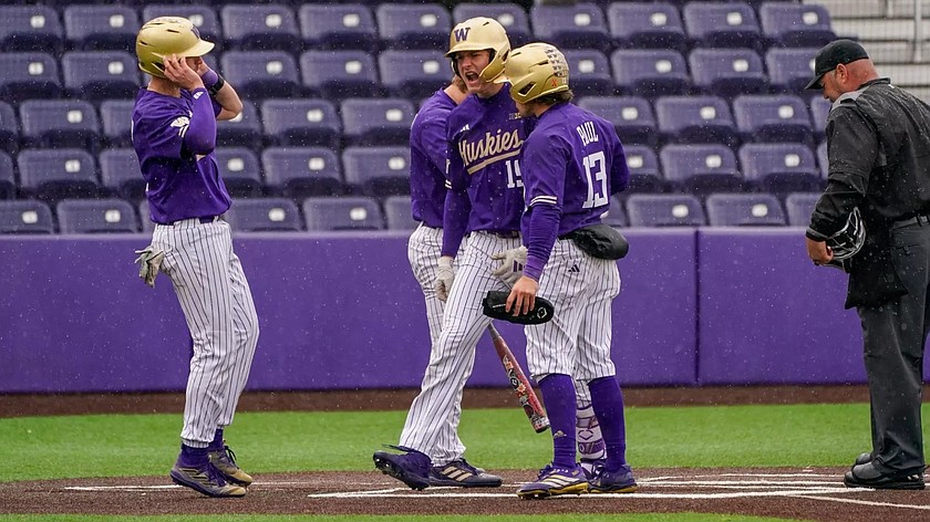 Huskies players gather at home plate as they celebrate one of their three home runs during Sunday's game against Northwestern.