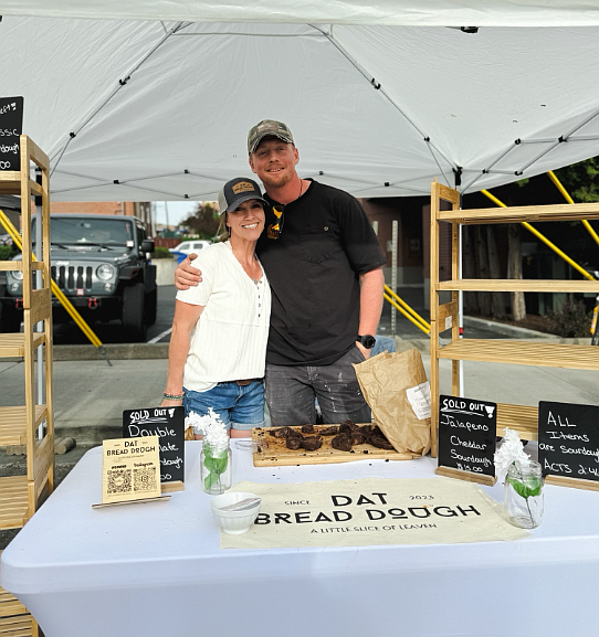 Lyndsey and Kyle Neufeld at their Dat Bread Dough booth at a local farmers' market, where customers snap up treats such as cinnamon rolls and cookies.