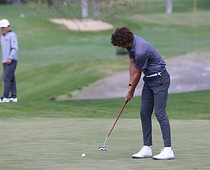 Grady Walker, in striped polo, puts his ball into the hole during a league match at Moses Lake Golf and Country Club.