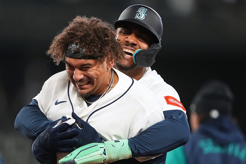 Seattle Mariners' Josh Naylor, front, is hugged by Julio Rodríguez, back, as they celebrate Naylor's game-winning single against the Athletics during the ninth inning of a baseball game, Wednesday, April 22, 2026, in Seattle.