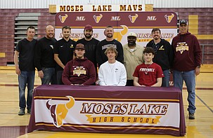 From left: Jeremiah Baker, Brady Jay and Carter Anderson are seated while surrounded by their coaches before signing their letter of intent to play football in college on Wednesday.