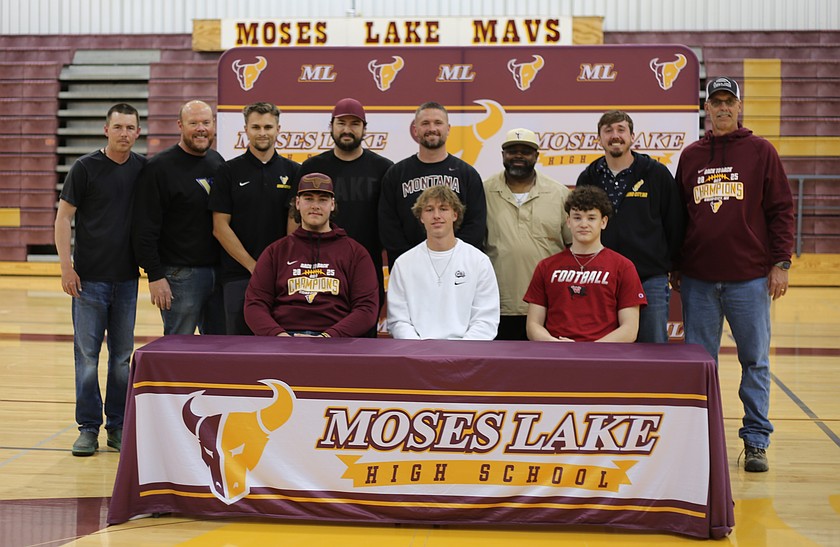 From left: Jeremiah Baker, Brady Jay and Carter Anderson are seated while surrounded by their coaches before signing their letter of intent to play football in college on Wednesday.