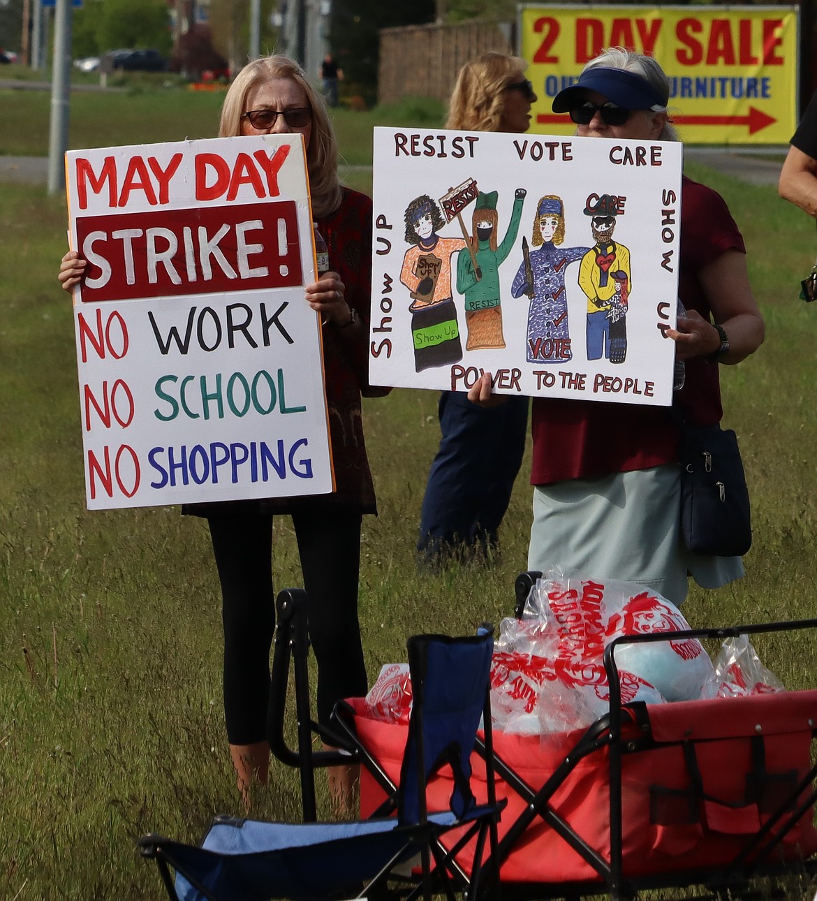 Two May Day protesters hold up their signs.