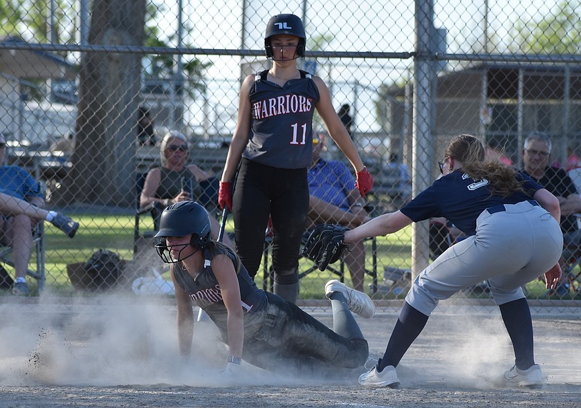 Warriors player Dani Isaak (1) slides in to steal home after an error while her teammate Josie Bayless (11) is up to bat and Lions pitcher Liana Spike (3) goes in to try and tag Isaak out.