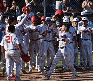 Huskies player Ryan Martinez (5) makes his way to home plate after hitting a home run with all of his teammates gathered around to celebrate during Tuesday’s game against Selah.
