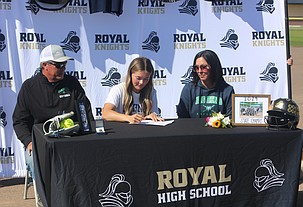 Seated with her parents, Jill Allred, in white, signs her letter of intent to play softball at Big Bend Community College.