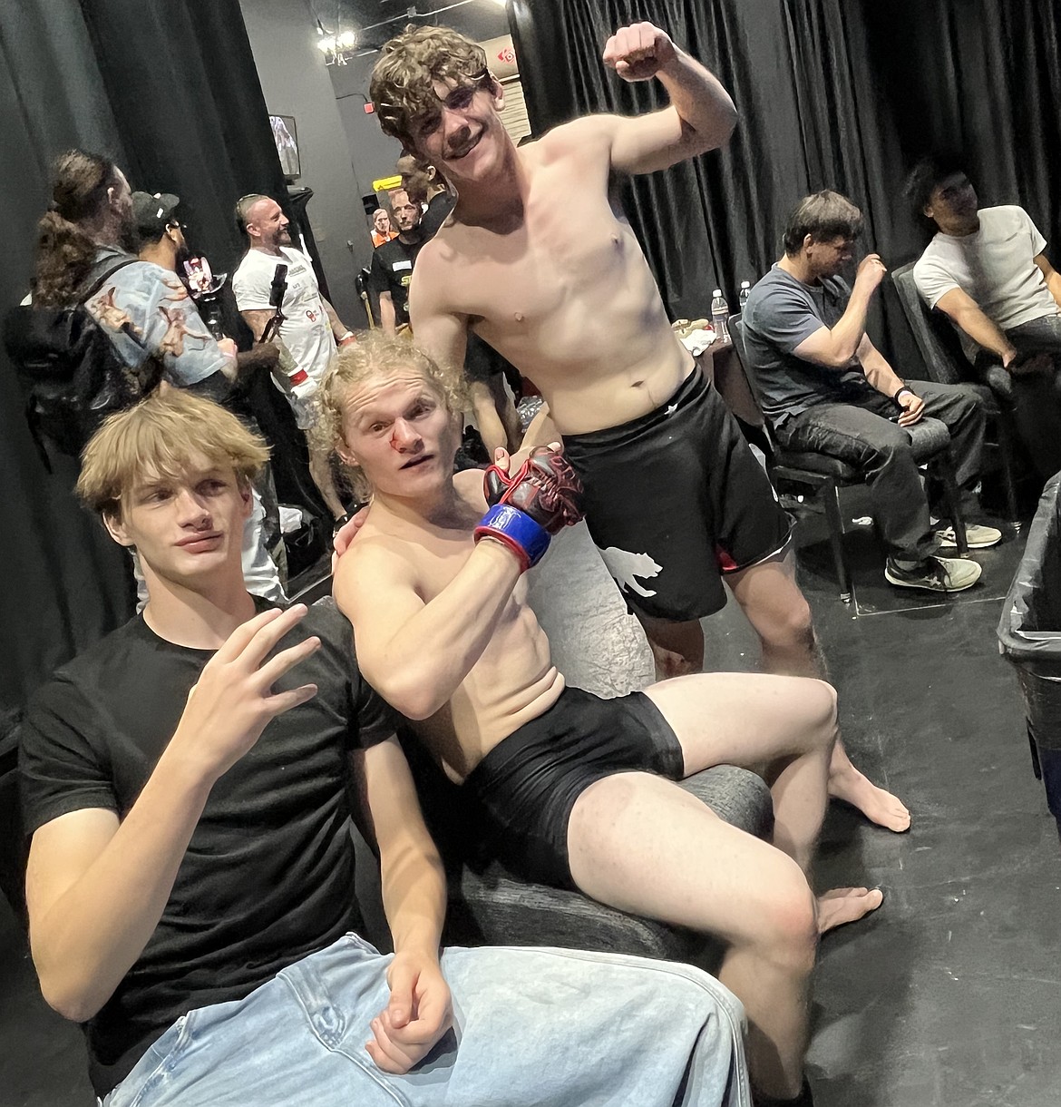 Jacob Guertin, middle, takes a photo with his opponent Brody Case, right, after their two-round MMA battle Saturday. Seated with them is Gannon Jordan, far left, who was in Guertin’s corner.