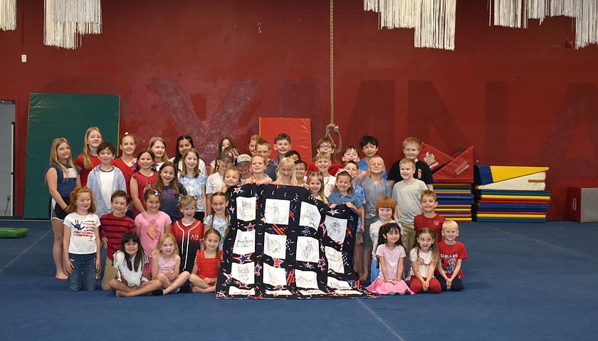 The students of AIM School show the quilt they made depicting people and symbols from American history in honor of the nation’s 250th birthday.
