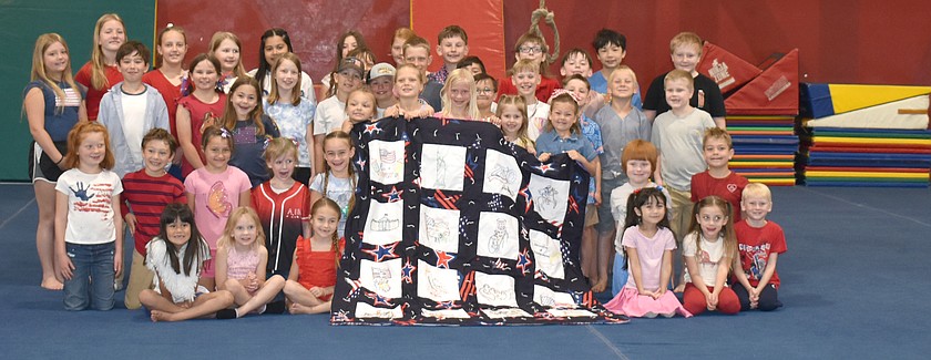 The students of AIM School show the quilt they made depicting people and symbols from American history in honor of the nation’s 250th birthday.