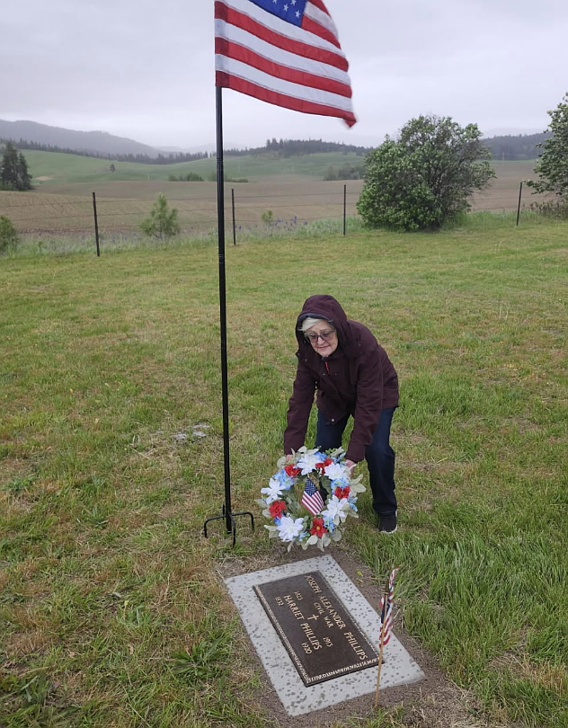 Joseph and Harriet Phillips' great-great-granddaughter Debbie Mitchell of Coeur d'Alene places a patriotic wreath on their grave marker Wednesday.