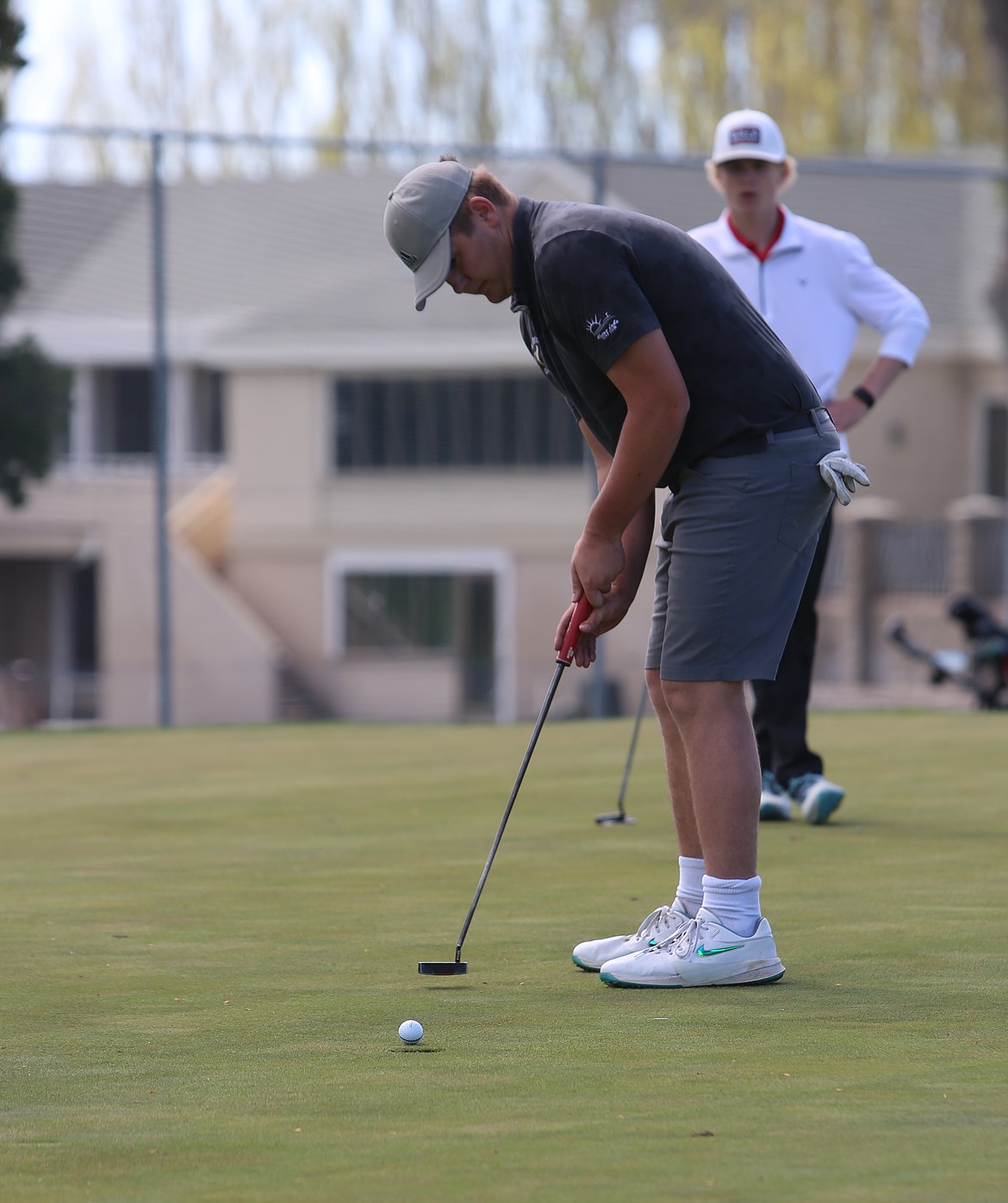 Christian Mathis, white shoes, puts the ball into the hole during a home golf match earlier this season.