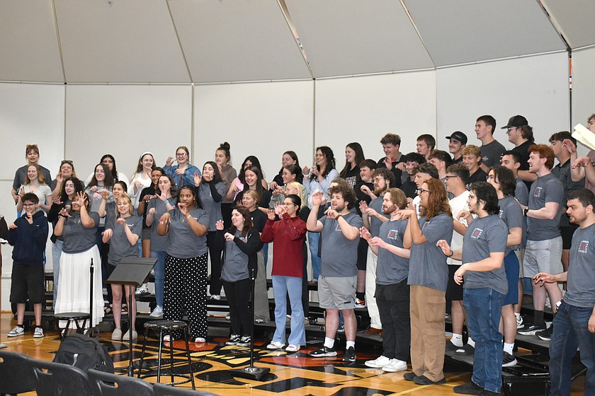 Singers from the Ephrata High School and Washington State University choirs warm up together with scales, vocal exercises and roaring tiger gestures.