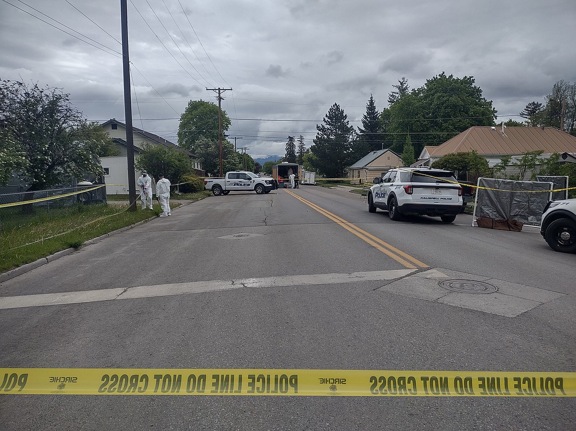 Investigators work behind police tape near the intersection of Second Street West and 10th Avenue West in Kalispell on Saturday, May 16. (Derrick Perkins/Daily Inter Lake)