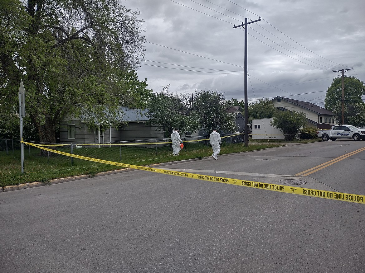 Investigators work behind police tape near the intersection of Second Street West and 10th Avenue West in Kalispell on Saturday, May 16. (Derrick Perkins/Daily Inter Lake)