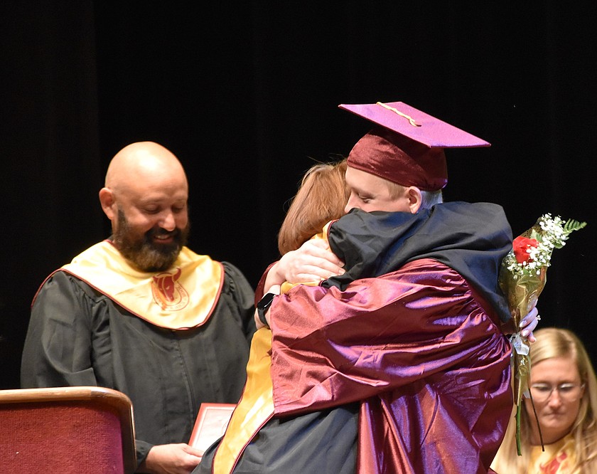 Blake Musso gives a big hug as he receives a bouquet and his diploma during Friday’s graduation ceremony.