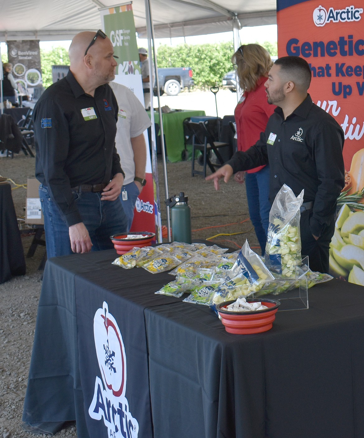 Okanagan Specialty Fruits sales representative Anthony Ortiz, right, tells a visitor to the Regenerative Ag Orchard Tech Showcase about OSF’s genetically engineered apples.