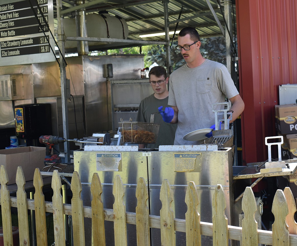 Ethan Small, right, shows Landon Noble how to work the fryer safely at the Smulligan’s barbecue booth at Spring Fest.