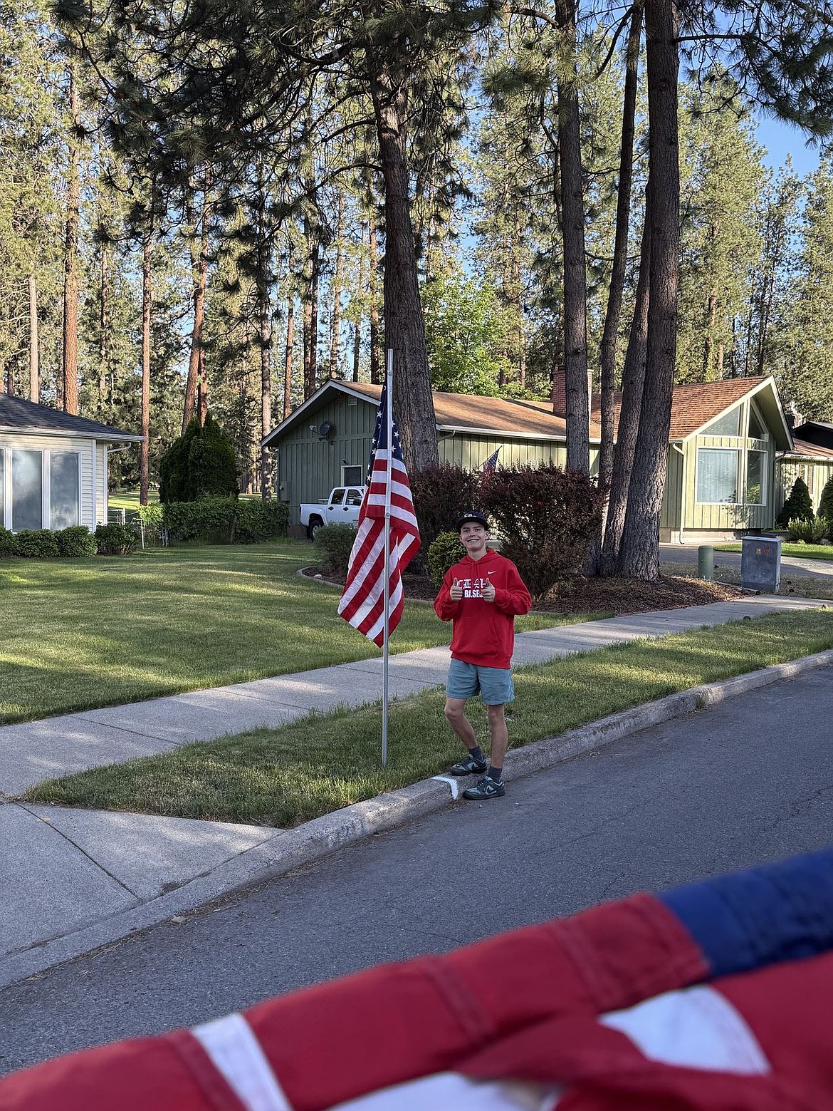 Courtesy photo  
Coeur d'Alene AA player Logan Strimback poses with a flag on Monday. Members of the Coeur d'Alene Lumbermen American Legion baseball program’s class AA team spent Memorial Day placing roughly 300 flags at residences in the community in the morning, then members of the 16U team collected them that night. The flag project is a partnership with the Lumbermen and the Kiwanis club. It honors the nation by displaying flags in neighborhoods in Coeur d'Alene, and helps develop a service attitude in the players.
