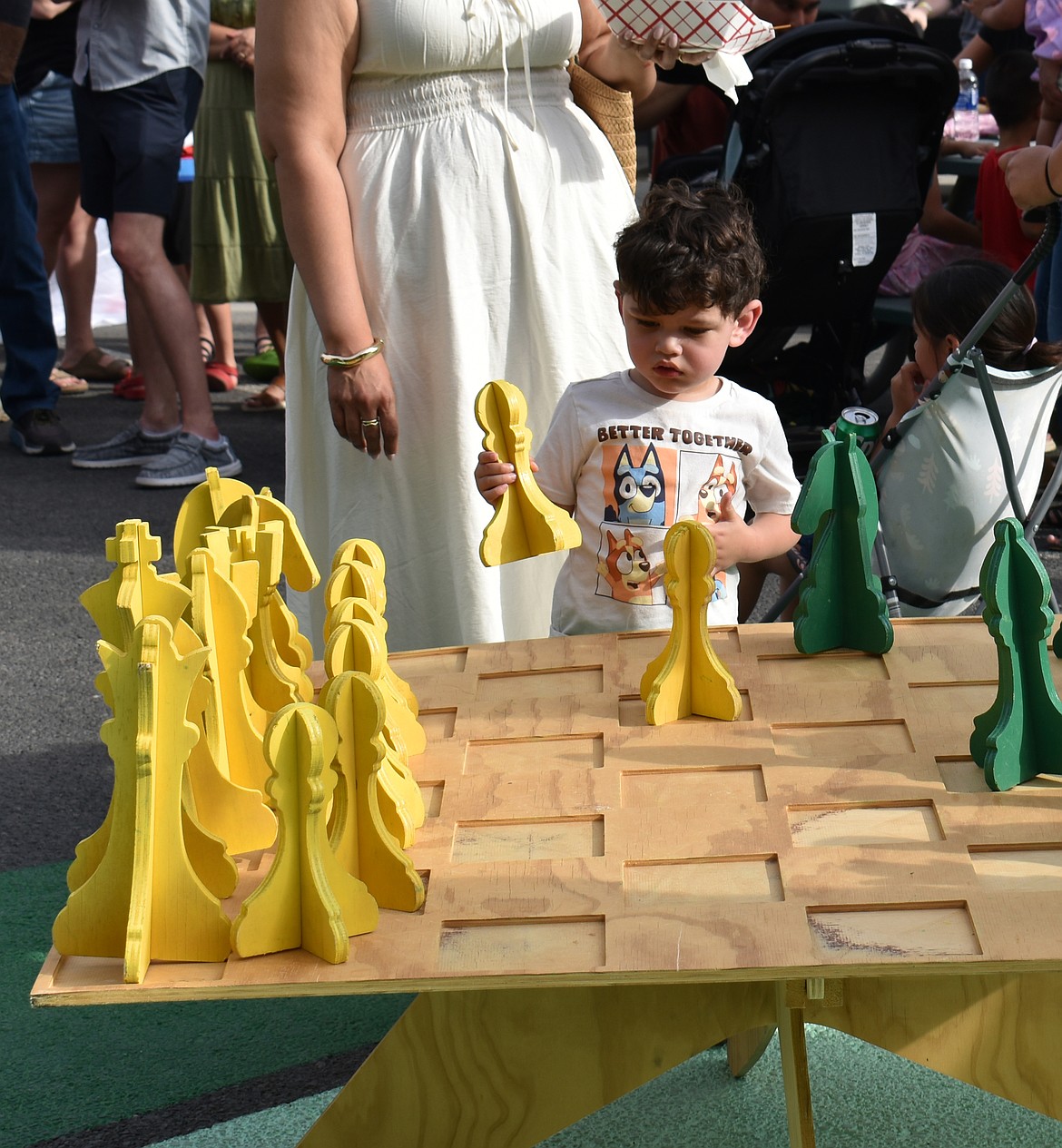 Two-year-old Ezra Ceballos isn’t sure what to do with an oversized chess piece at the B Street Bash in Quincy Thursday.