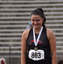 Saige Galbreath, a senior from the Broncos, smiles as she stands on the podium at state after receiving her third-place medal for shot put.