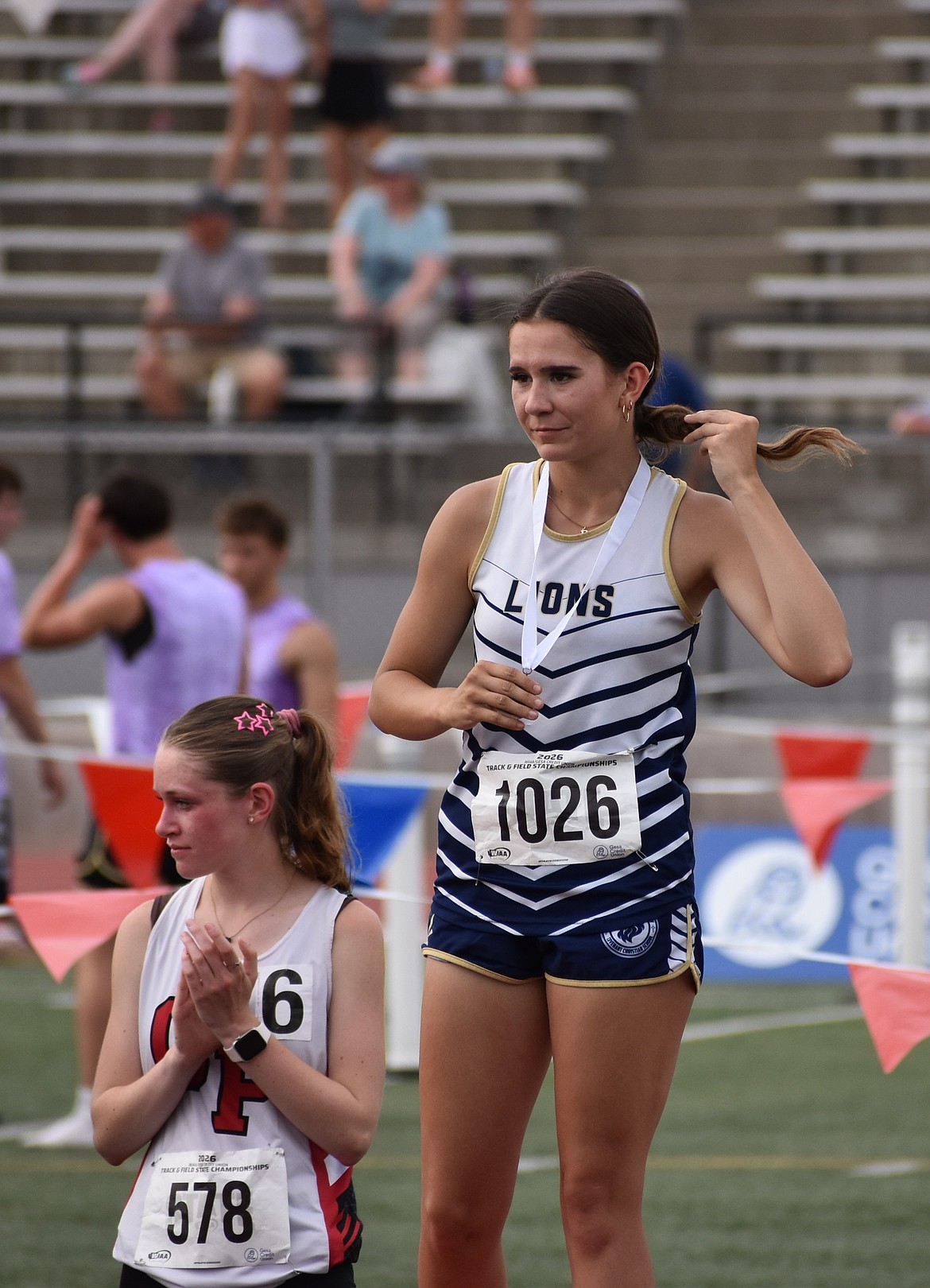 Lions senior Brynlynn King puts on her medal after earning seventh place in the 1600 meters at state.