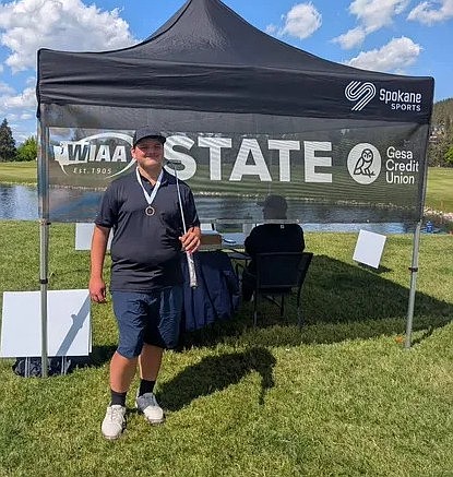 Eli Madigan holds his club over his shoulder after receiving his fifth place medal at the 1B state golf championship.