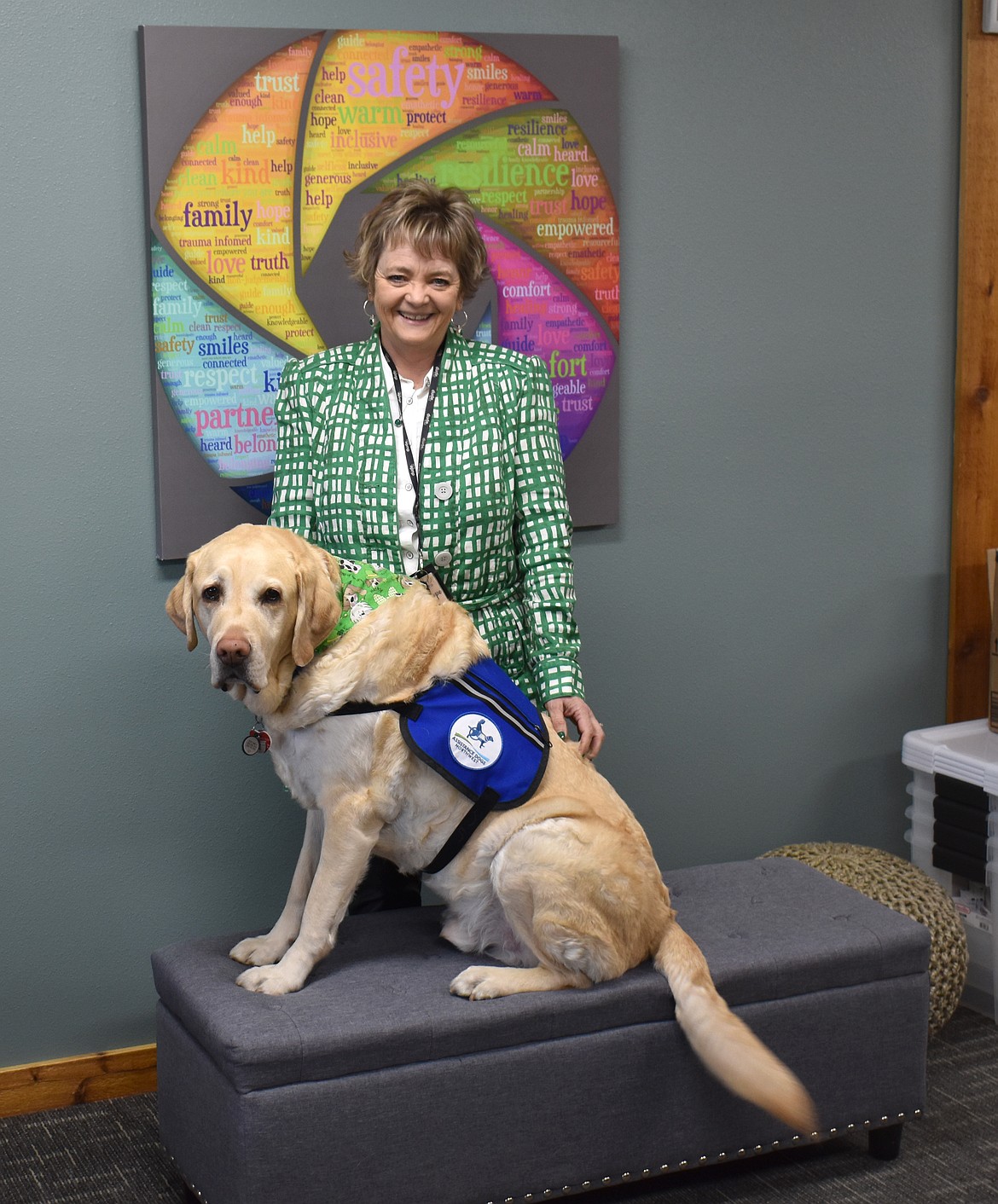 Suzi Fode stands in the New Hope office last year with comfort dog Valor. Valor, who joined New Hope in 2020, sits with children during interviews about abuse, and goes with them when they have to testify in court.