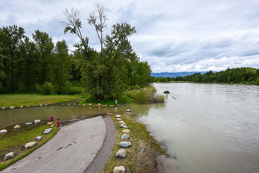 People stand along the banks of the swollen Flathead River at the Old Steel Bridge Fishing Access in Evergreen on Tuesday, June 2. (Casey Kreider/Daily Inter Lake)