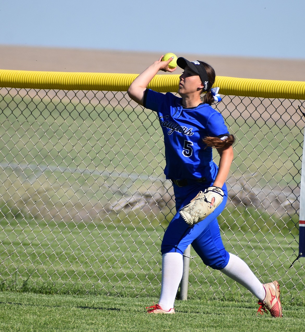 Amaya Erickson from the Cougars throws the softball back toward the diamond from the outfield during her senior season.