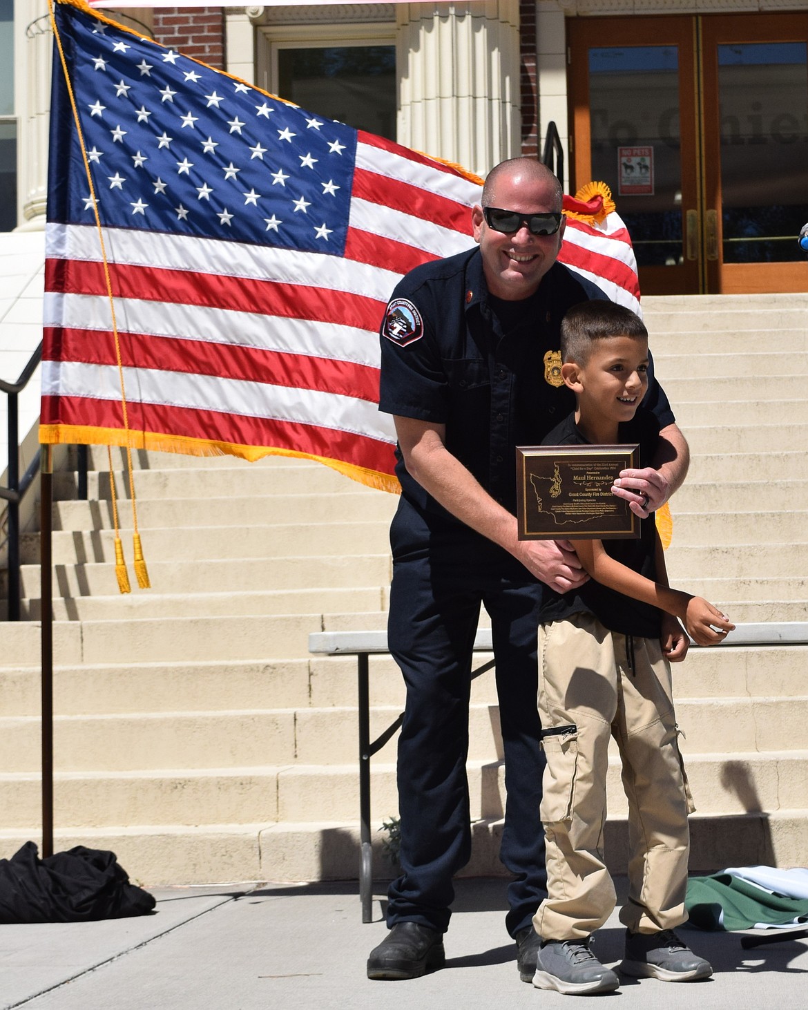 After making a quick run up the courthouse stairs, Grant County Fire District 7 Chief for a Day Maui Hernandez accepts his plaque from GCFD 7 Chief Erick Brittain.
