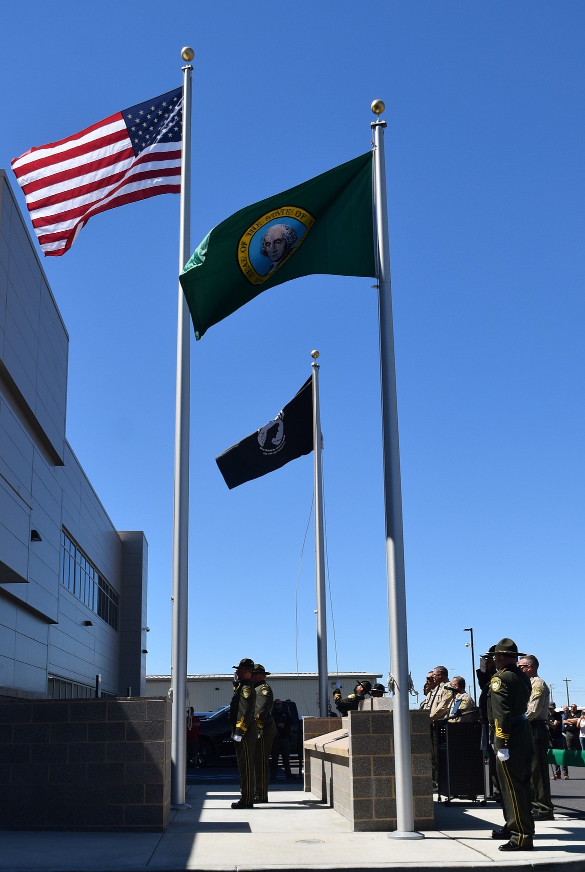 Grant County Sheriff’s Office deputies and Moses Lake Police Department officers place the flags outside the jail facility Wednesday as part of the ribbon cutting ceremony.