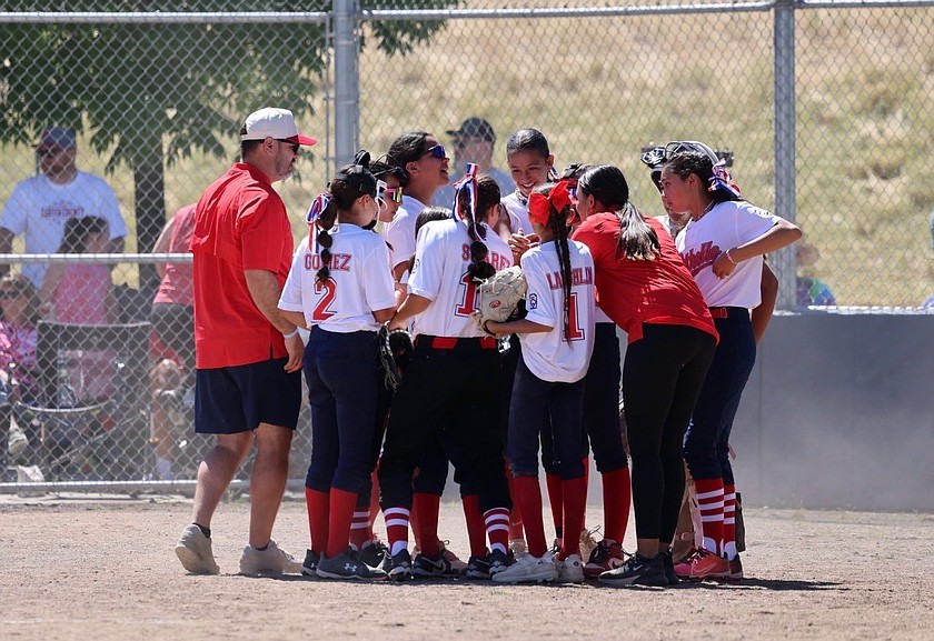 Players and coaches from Othello 12u softball celebrate their victory around home plate.