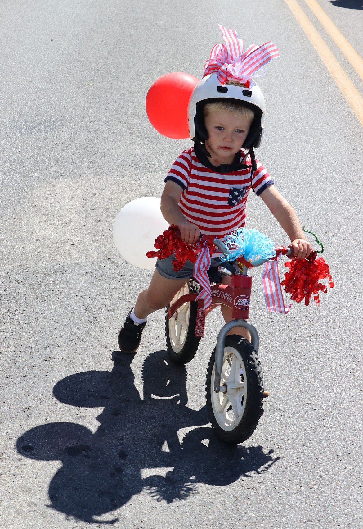 Jensen Tompkins casts a shadow as he rides his bike in the Kiddie Parade.